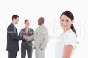 Smiling saleswoman with three colleagues behind her