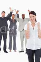 Successful businesswoman with cheering colleagues behind her