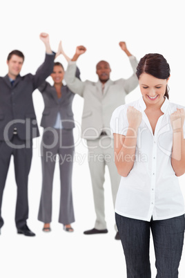 Triumphant businesswoman with cheering colleagues behind her