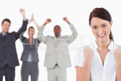 Victorious businesswoman with cheering team behind her