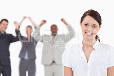 Smiling saleswoman with cheering associates behind her