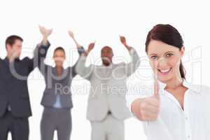 Saleswoman with cheering colleagues giving thumb up