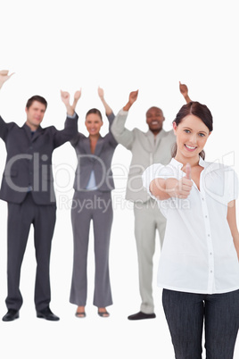 Businesswoman with cheering colleagues behind her giving approva