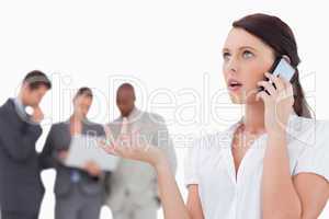 Saleswoman talking on the phone with colleagues behind her