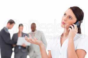 Tradeswoman talking on the phone with colleagues behind her