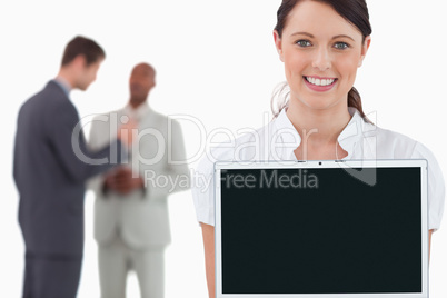 Tradeswoman showing laptop with colleagues behind her