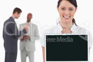 Tradeswoman showing laptop with colleagues behind her