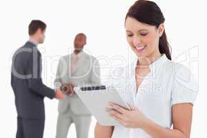 Saleswoman with tablet and colleagues behind her