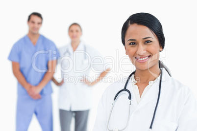 Smiling female doctor with colleagues behind her