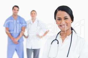 Smiling female doctor with colleagues behind her