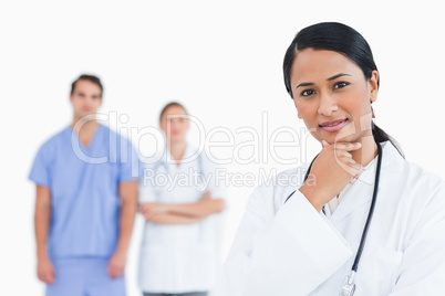 Thoughtful doctor with colleagues behind her