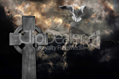 Graveyard cross with seagull against storm clouds