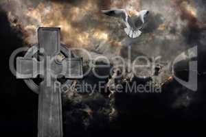 Graveyard cross with seagull against storm clouds