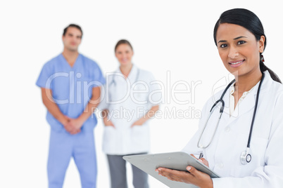 Doctor with notepad and colleagues behind her