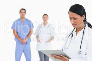 Doctor taking notes with staff behind her
