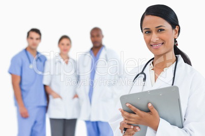 Female doctor with clipboard and staff members behind her