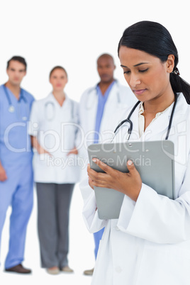 Female doctor reading notes with staff members behind her