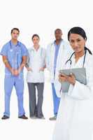 Female doctor with clipboard and colleagues behind her