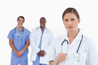 Serious looking female doctor with male colleagues behind her