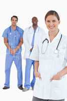 Smiling female doctor with male colleagues behind her