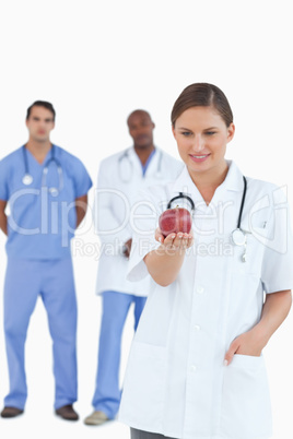 Doctor looking at apple with colleagues behind her