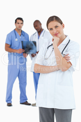 Doctor in thinkers pose with colleagues behind her
