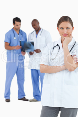 Thinking doctor with colleagues behind her