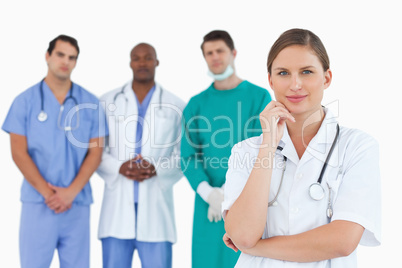 Thoughtful doctor with male colleagues behind her