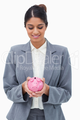 Smiling bank employee looking at piggy bank in her hands