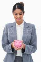Smiling bank employee looking at piggy bank in her hands