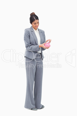 Smiling female banker putting bank note into piggy bank
