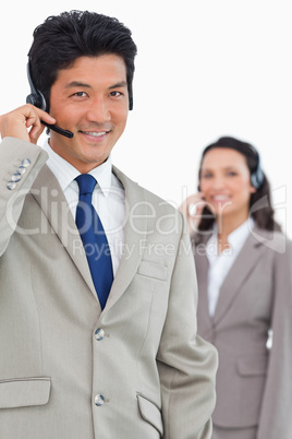 Smiling customer support employee with colleague behind him