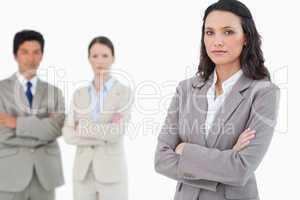 Confident saleswoman with arms folded and colleagues behind her