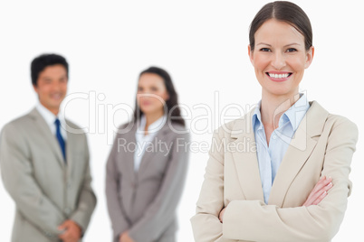 Smiling saleswoman with arms folded and associates behind her