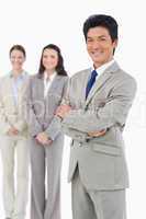 Confident smiling businessman with his employees behind him