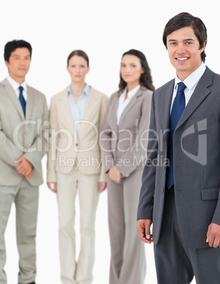 Smiling young salesman with his team behind him