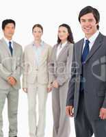 Smiling young salesman with his team behind him