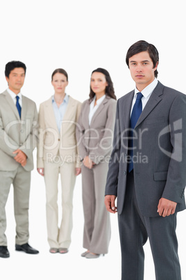 Serious young businessman with team behind him