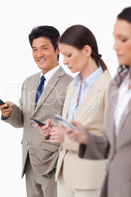 Smiling businessman with cellphone next to colleagues