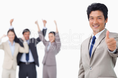 Businessman giving thumb up while getting celebrated