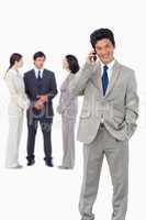 Businessman on cellphone with team behind him