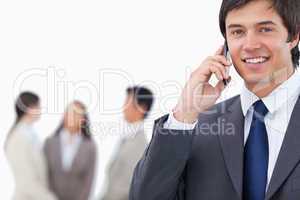 Smiling salesman on his cellphone with team behind him