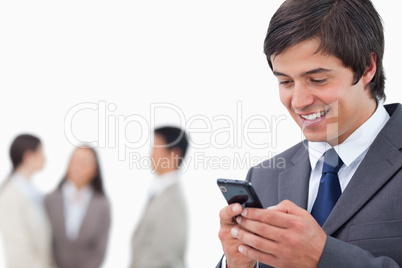 Salesman writing text message with team behind him