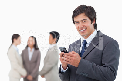 Salesman holding cellphone with team behind him