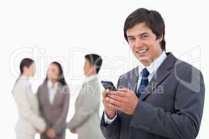 Salesman holding cellphone with team behind him