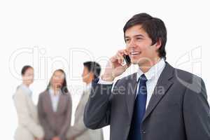 Salesman talking on cellphone with colleagues behind him