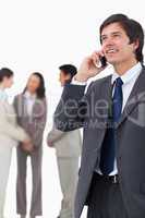 Salesman talking on mobile phone with team behind him