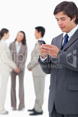 Salesman reading text message on cellphone with team behind him