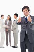Salesman giving thumbs up with team behind him