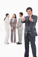 Salesman giving thumbs up with colleagues behind him